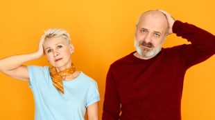 Horizontal shot of middle aged lady and her unshaven bald elderly husband expressing surprised reactions, holding hands on head, having confused clueless look. Are you in a situationship - article Silver Magazine www.silvermagazine.co.uk