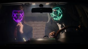 Two shady looking characters in a car wearing masks with sinister neon faces. Avoid scams and online threats article Silver Magazine www.silvermagazine.co.uk