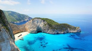 Shows beautiful bay with blue sea and idyllic holiday vibes, beach in Zakynthos Greece. Best for island hopping article on Silver Magazine www.silvermagazine.co.uk