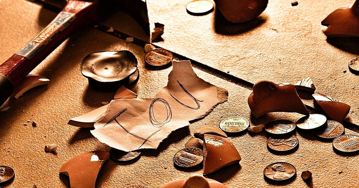 Broken piggy bank with notes and coins everywhere and an IOU note