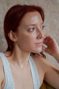 Headshot of Deidre Olson. She is lighter skinned with short cropped hair and a simple white tank top. She is looking to the side