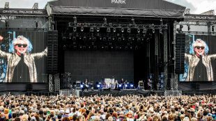 Image shows a wide angle shot of an outdoor music stage with Blondie performing