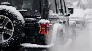 Shows cars lined up on the road in the snow. Drive safely in the snow Silver Magazine www.silvermagazine.co.uk