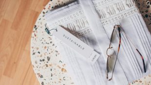 Embroidered piece of clothing on a tabletop foldede up with a label saying Sustainability showing. Ethical v fast fashion - article Silver Magazine www.silvermagazine.co.uk