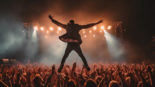 Glastonbury Music Festival, outdoor stage, performing artist in a dramatic pose, enthusiastic crowd, illuminated by stage lights. Emerging talent competition Glastonbury Festival article on Silver Magazine www.silvermagazine.co.uk