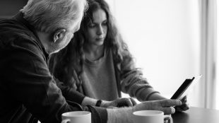 An older man and a younger woman looking at a photo album together. Picture in black and white.
