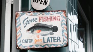 A hung up shop sign that reads gone fishing catch you later on it.