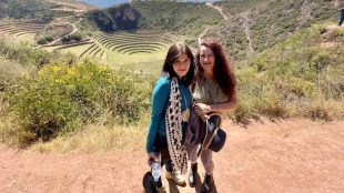 Mother and daughter stand side by side infornt of Machu Picchu, in Peru.