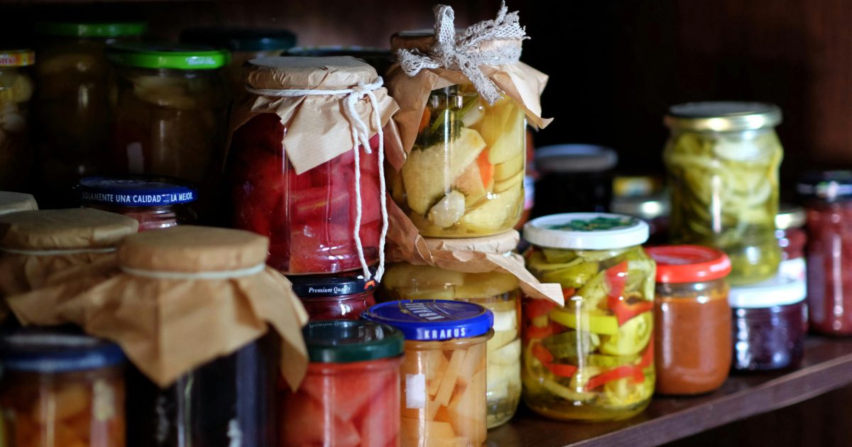 This image shows food stored in jars lined up in a cupboard.