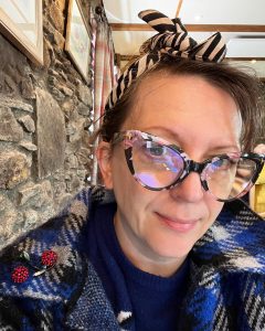 Portrait of author Flic Everett showing her flowery framed reading glasses