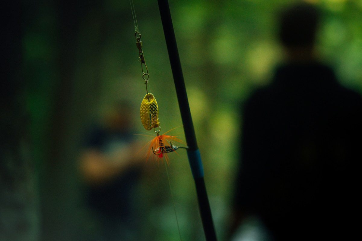 A close-up image of a fly fishing rod, where the fly is yellow and orange. 