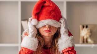 image shows a fed up woman pulling a santa hat down over her face, had enough of Christmas