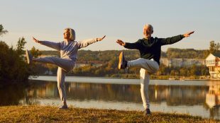Active sporty mature couple doing stretching exercising in nature. Happy smiling older man and woman in sportswear having sport workout in park. Outdoors training and fitness over 50 concept.