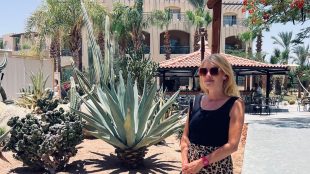 Juliette standing with an obvious holiday background behind her, plants and sunlight etc