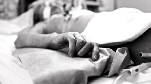 Hand of extremely exhausted patients dying in a hospital bed. Black and white conceptual photography.