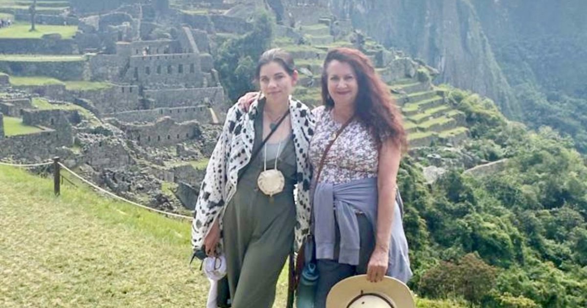 Mother and daughter stand side by side infornt of Machu Picchu, in Peru. 