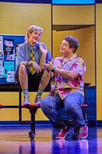 Two characters from Mean Girls sing a duet together on a school bench.