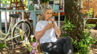 A mature woman sitting outside and drinking her cocktail