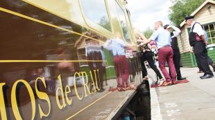 image shows old fashioned train carriage with people boarding it, dressed smartly