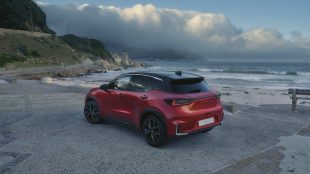 A Red Lexus LBX car on a pavement near the beach.