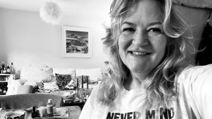 black and white image showing Sam Harrington-Lowe wearing a Never Mind the Bollocks Tshirt and smiling