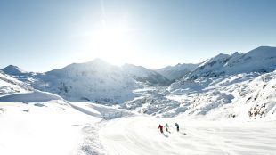 Skiing at the Obertauern. Three people skiing across a snowy mountain landscape