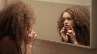 teenage girl looking in a mirror concerned