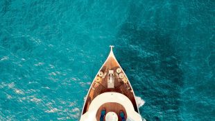 Image of yacht prow from above on beautiful turqoise sea. TM1444-SIL WHy yachts are perfect retirement plan article on Silver Magazine www.silvermagazine.co.uk