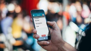 Hand holding up mobile device looking at the medical card app. Travel with medical information World Medical Card app - article Silver Magazine www.silvermagazine.co.uk