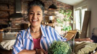 Mature woman unpacking basket in home kitchen with happy smile. Upgrade your home - Silver Magazine www.silvermagazine.co.uk