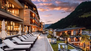 Fancy hotel resort in alpine setting, summer time. Green hills behind, and snowy mountains further in the distance. Hotel Edelweiss in summer - article Silver Magazine www.silvermagazine.co.uk