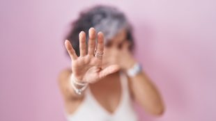 Middle age woman with grey hair standing over pink background covering eyes with hands and doing stop gesture with sad and fear expression. embarrassed and negative concept.